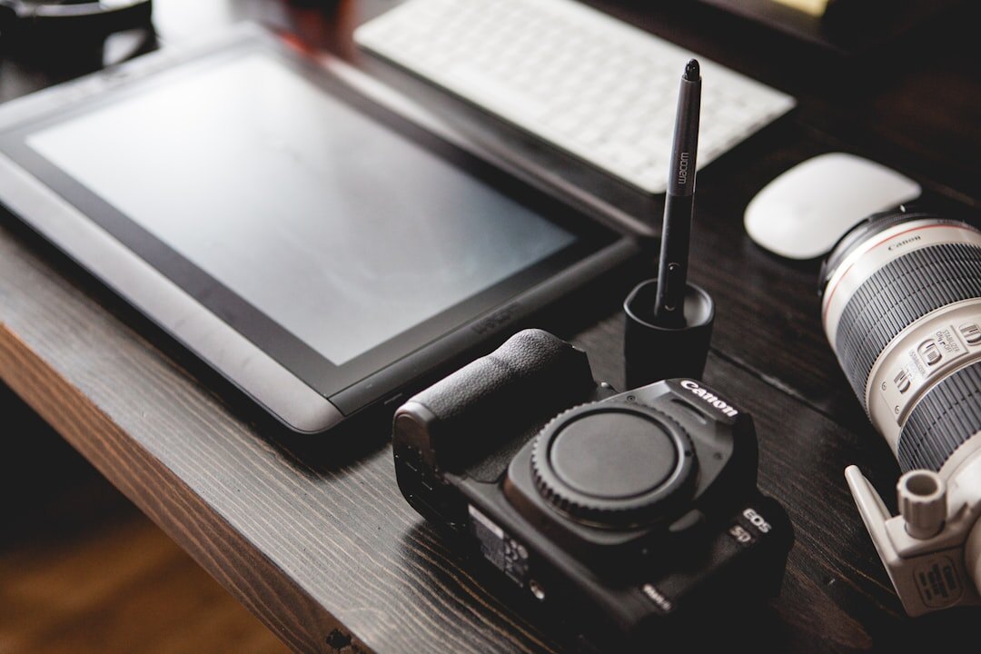 Professional camera and lenses on a wooden desk with notebook
